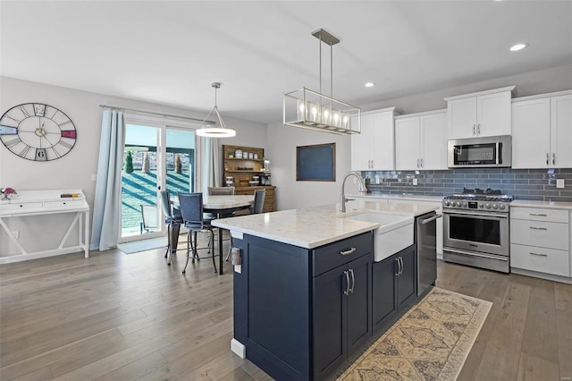 kitchen featuring sink, pendant lighting, a center island with sink, white cabinets, and appliances with stainless steel finishes