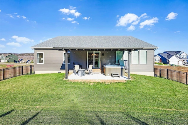 rear view of house with a yard, a patio, and a hot tub