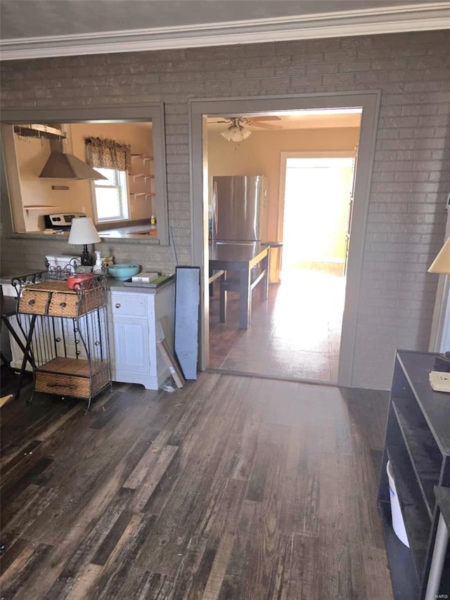 kitchen featuring dark hardwood / wood-style floors, stainless steel refrigerator, ceiling fan, and brick wall