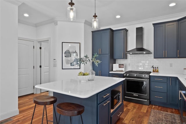 kitchen featuring wall chimney range hood, blue cabinetry, a kitchen island, dark hardwood / wood-style flooring, and stainless steel appliances