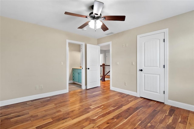 unfurnished bedroom featuring hardwood / wood-style floors, ceiling fan, and ensuite bath