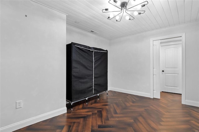 empty room featuring dark parquet floors, wooden ceiling, and a notable chandelier