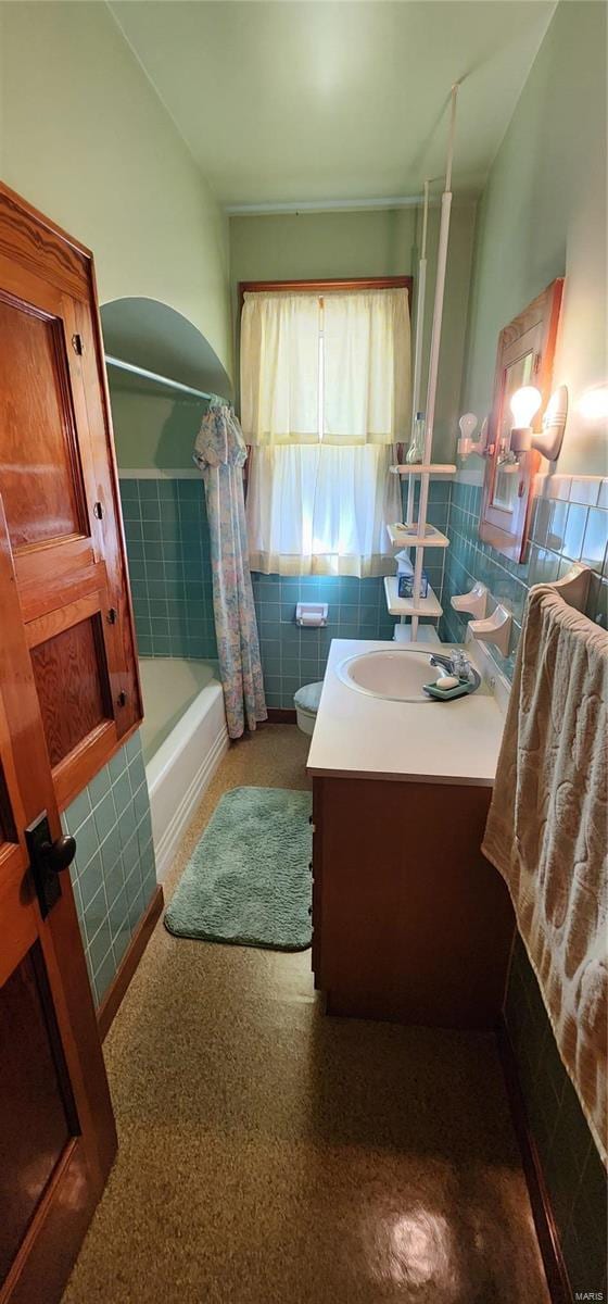 full bathroom with vanity, toilet, tile walls, and shower / tub combo