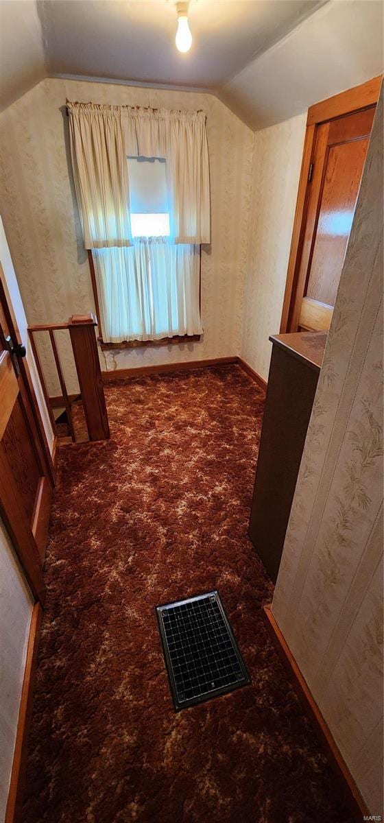 interior space featuring dark colored carpet and lofted ceiling