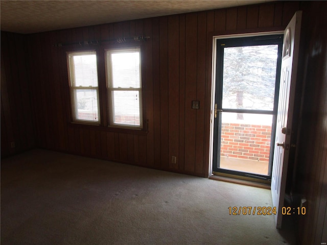 carpeted spare room featuring wood walls