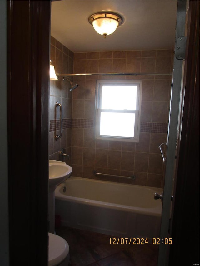 bathroom with tiled shower / bath combo and toilet