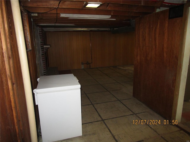 basement with refrigerator and wood walls