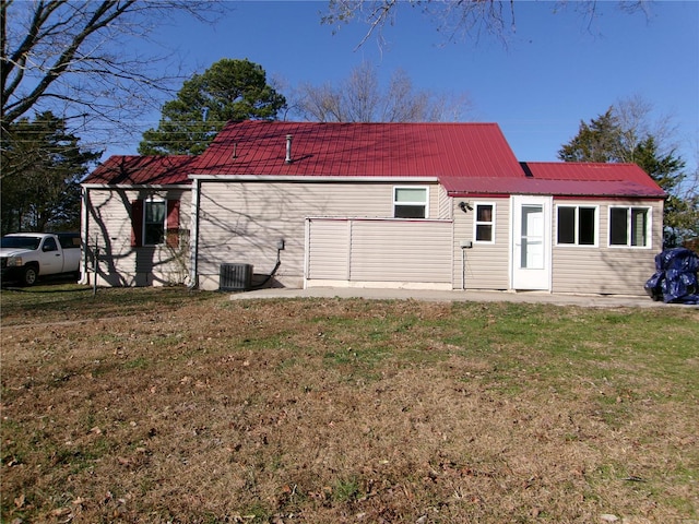 rear view of house with cooling unit and a lawn