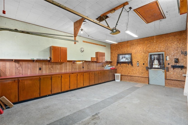 garage featuring a garage door opener and wooden walls