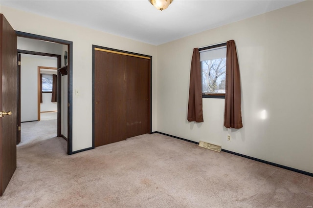 unfurnished bedroom with light colored carpet and a closet