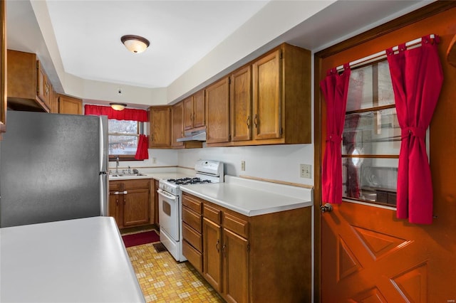 kitchen with white range with gas cooktop, stainless steel fridge, and sink