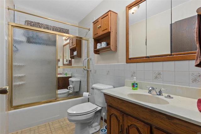 full bathroom featuring toilet, vanity, tile walls, and combined bath / shower with glass door