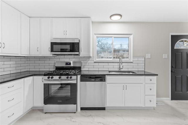 kitchen with tasteful backsplash, white cabinetry, appliances with stainless steel finishes, and sink