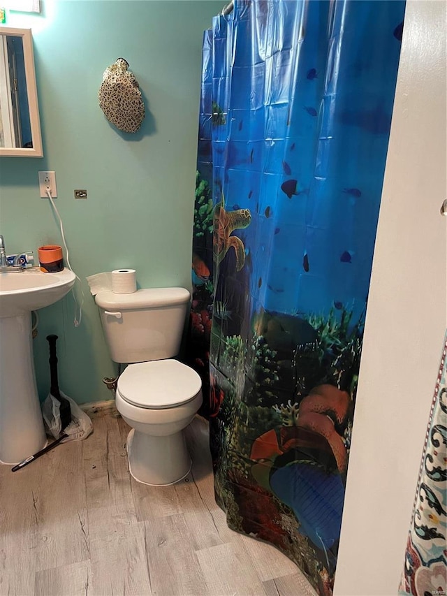 bathroom featuring hardwood / wood-style flooring, toilet, sink, and a shower with shower curtain