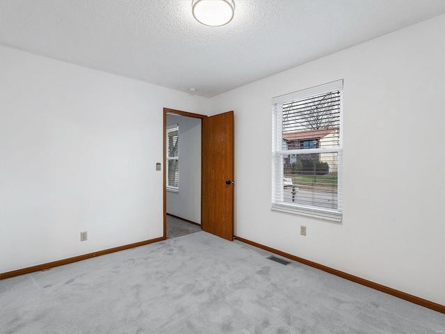 unfurnished room featuring light carpet and a textured ceiling