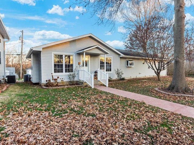 view of front of property featuring an AC wall unit, a front lawn, and central AC unit