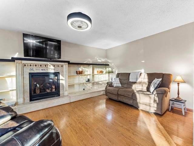 living room with a fireplace, hardwood / wood-style floors, and a textured ceiling