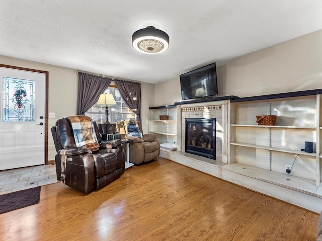 living room with a textured ceiling, wood-type flooring, and a fireplace