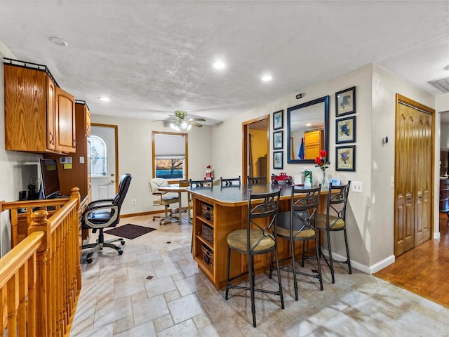 interior space with kitchen peninsula, a kitchen breakfast bar, light wood-type flooring, and ceiling fan