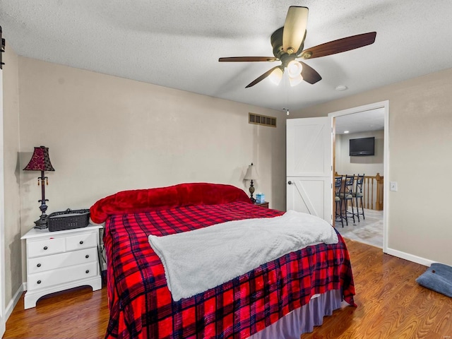 bedroom featuring hardwood / wood-style floors, a textured ceiling, and ceiling fan