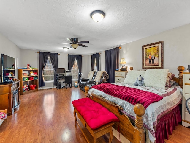 bedroom featuring ceiling fan, wood-type flooring, and a textured ceiling