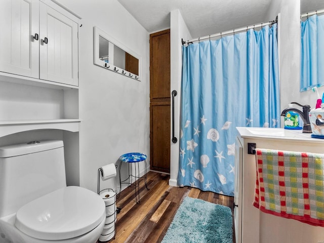 bathroom with hardwood / wood-style floors, vanity, a textured ceiling, and toilet