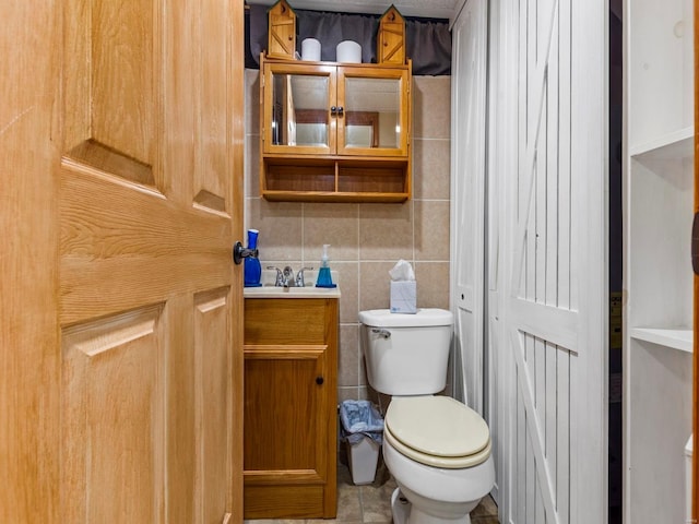 bathroom featuring tile patterned floors, vanity, toilet, and tile walls