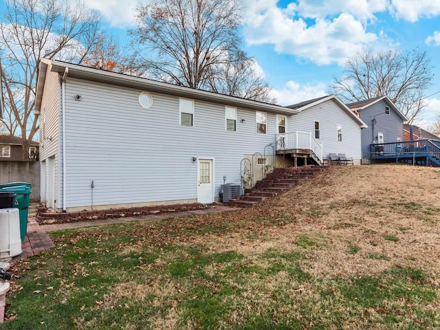 rear view of house with a lawn, a garage, and a wooden deck