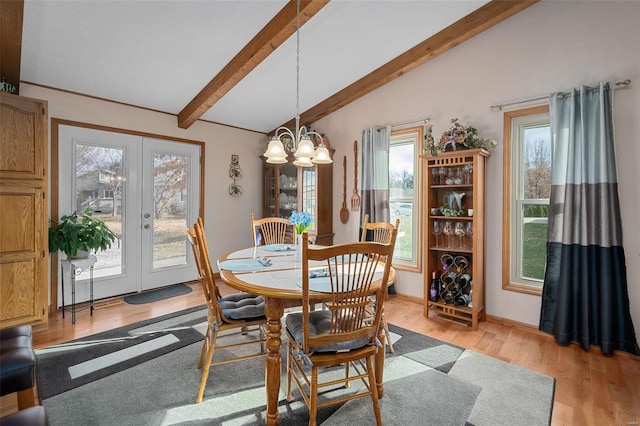 dining space with a notable chandelier, vaulted ceiling with beams, a healthy amount of sunlight, and light hardwood / wood-style flooring