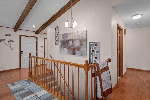 hallway with vaulted ceiling with beams, a textured ceiling, an inviting chandelier, and light hardwood / wood-style flooring