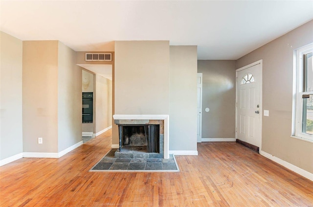 unfurnished living room with light hardwood / wood-style floors and a tiled fireplace