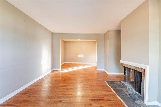 unfurnished living room with wood-type flooring and a tile fireplace