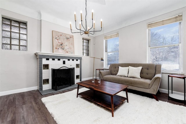 living room featuring dark hardwood / wood-style flooring, an inviting chandelier, and a brick fireplace