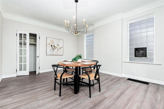 dining area with hardwood / wood-style floors and an inviting chandelier