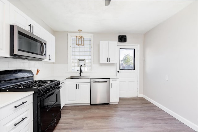 kitchen featuring sink, white cabinets, decorative light fixtures, and appliances with stainless steel finishes