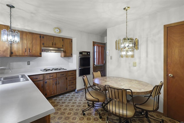 kitchen with white gas stovetop, sink, a notable chandelier, black oven, and hanging light fixtures