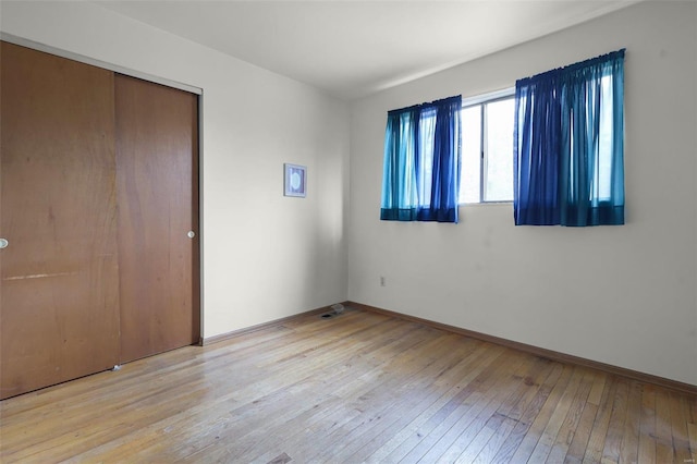 unfurnished bedroom featuring light hardwood / wood-style flooring and a closet