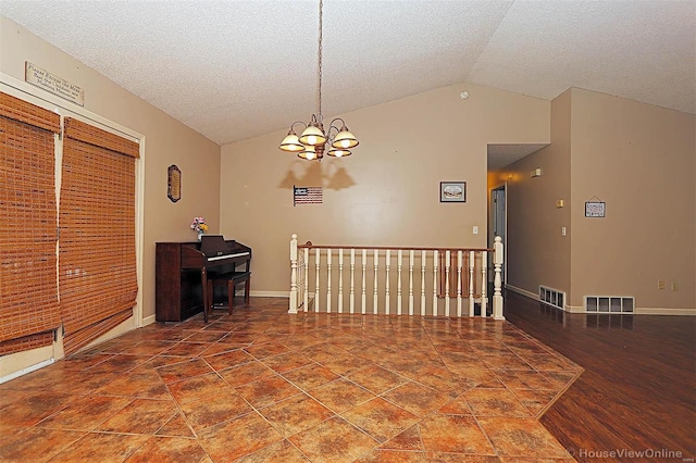 unfurnished room with a textured ceiling, vaulted ceiling, and a notable chandelier