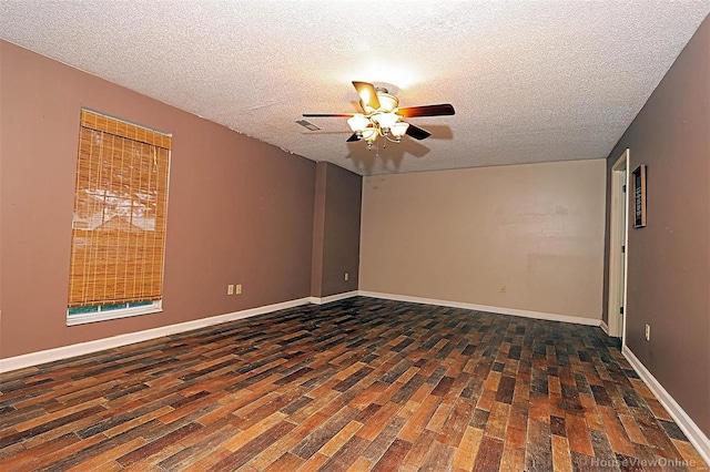 empty room featuring ceiling fan, dark wood-type flooring, and a textured ceiling