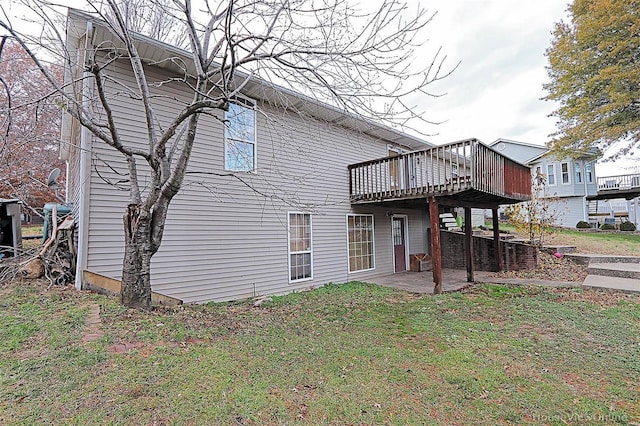 rear view of property with a deck, a patio area, and a lawn