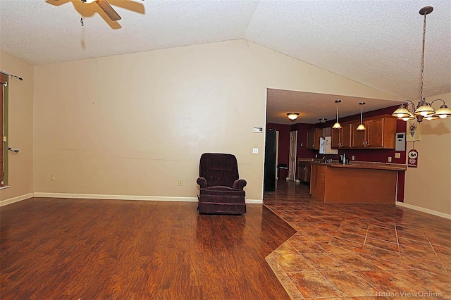 unfurnished room with a textured ceiling, ceiling fan with notable chandelier, dark wood-type flooring, and vaulted ceiling