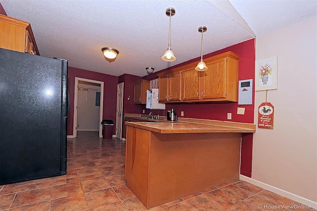 kitchen featuring decorative light fixtures, black refrigerator, kitchen peninsula, and a textured ceiling