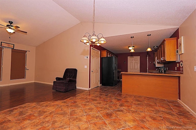 kitchen featuring hanging light fixtures, black refrigerator with ice dispenser, kitchen peninsula, vaulted ceiling, and ceiling fan with notable chandelier