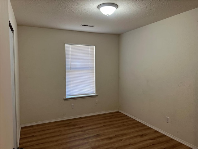 empty room featuring a textured ceiling and dark hardwood / wood-style floors