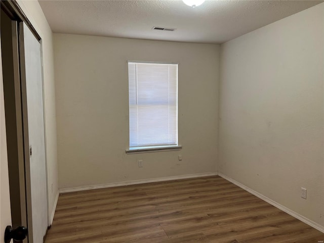 empty room with a textured ceiling and dark wood-type flooring