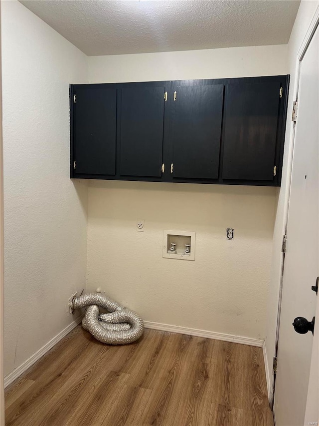 laundry area with hardwood / wood-style floors, cabinets, hookup for a gas dryer, washer hookup, and a textured ceiling