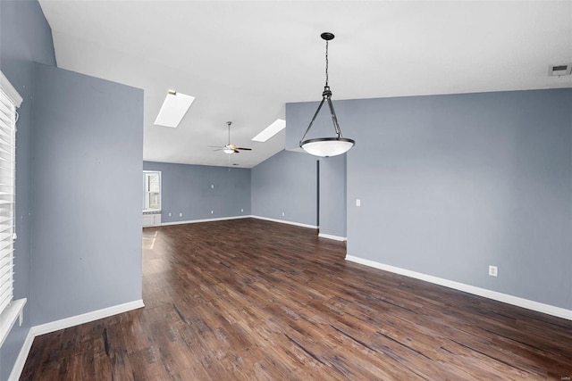 unfurnished living room with a fireplace, dark hardwood / wood-style floors, ceiling fan, and vaulted ceiling with skylight