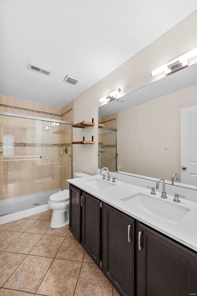 bathroom featuring tile patterned floors, a shower with door, vanity, and toilet