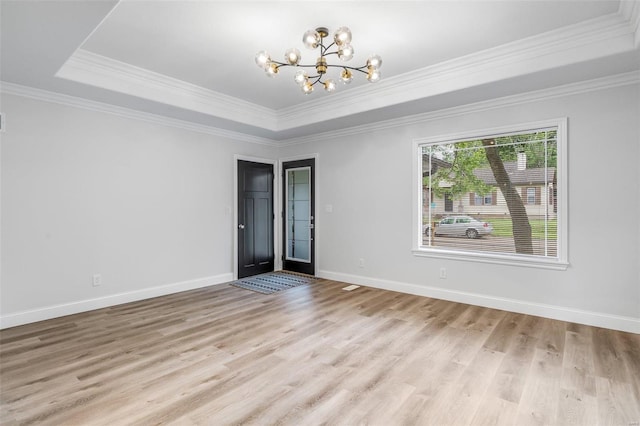 unfurnished room featuring a raised ceiling, crown molding, light hardwood / wood-style flooring, and a chandelier