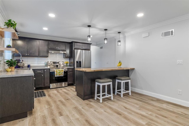 kitchen with decorative light fixtures, stainless steel appliances, ornamental molding, and a breakfast bar area